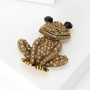 Vue détaillée de la broche grenouille avec strass ambrés et grands yeux noirs en gemme