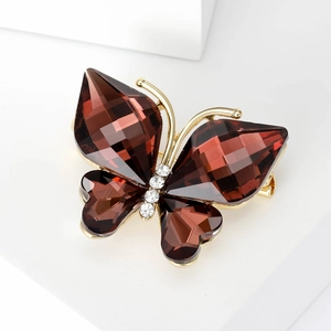 Close-up of golden butterfly brooch featuring brown faceted crystals and clear rhinestones