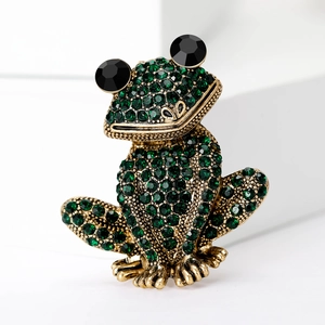 Vue macro d'une broche grenouille en cristal vert avec placage or et strass brillants
