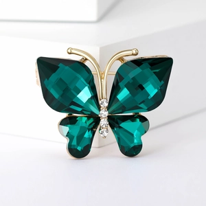Macro shot of green crystal butterfly brooch with golden alloy frame and white rhinestones