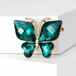 Detail of golden butterfly brooch with dark green crystals and clear sparkling rhinestones