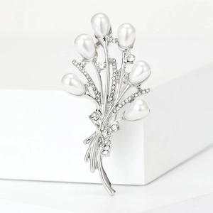 Détail d'une broche bouquet argentée élégante ornée de perles blanches et d'oxydes de zirconium