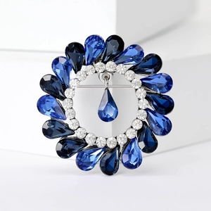 Close-up of vintage round brooch with dark blue teardrop crystals and silver rhinestones
