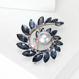 Dettaglio ravvicinato di una spilla a spirale con perla grigio argento e cristalli blu