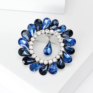 Detail of vintage round alloy brooch with blue rhinestones and dangling water drop charm
