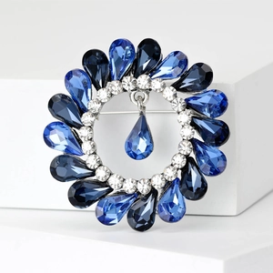 Detailed macro view of vintage round rhinestone brooch with blue crystals and water drop pendant