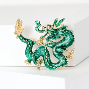 Detail of green enamel dragon brooch with golden scales and refined metallic texture