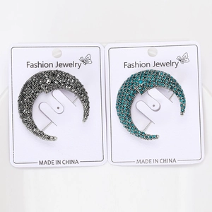 Macro detail of crescent moon brooches with sparkling rhinestones in silver and blue