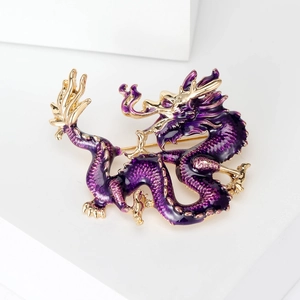 Close-up detail of dragon brooch featuring purple enamel work and golden metallic finish