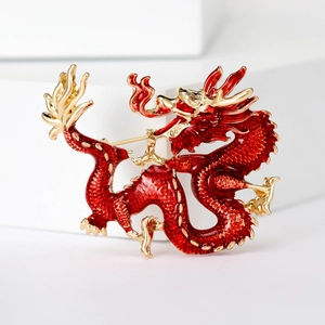 Detailed close-up of a red and gold enamel Chinese dragon brooch on a white stand