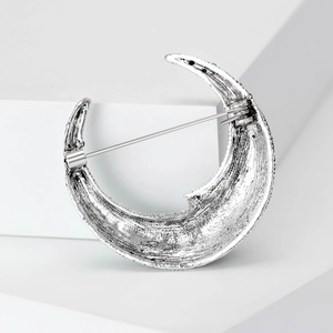 Silver crescent moon brooch featuring a hammered metal texture and secure safety pin back