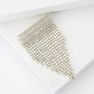 Détail d'une élégante broche dorée avec cristaux rectangulaires et franges scintillantes