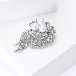 Detailed view of elegant silver floral brooch with white pearls and sparkling rhinestones