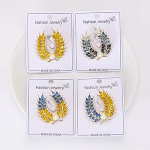 Détail de quatre broches d'épis de blé avec strass et perles sur plateau blanc