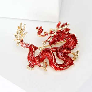 Detailed close-up of a red enamel dragon brooch with shiny golden metallic edges