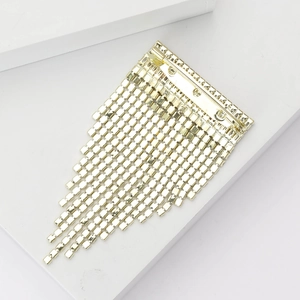Détail d'une broche à franges dorées avec plaques métalliques et épingle de sûreté