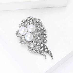 Detailed view of silver flower brooch with three pearls and sparkling rhinestones