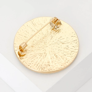 Broche ronde dorée avec dos en métal texturé rayonnant et détail de fermoir à épingle