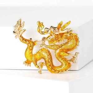 Close-up of golden dragon enamel brooch showing intricate scales and metallic texture