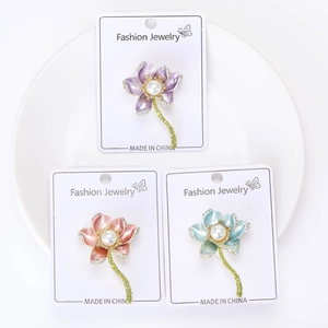 Detailed view of three lotus brooches with enamel petals, pearls, and rhinestones