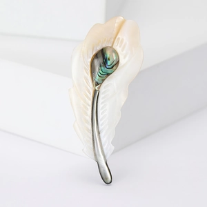 Détail macro d'une broche plume de luxe en nacre blanche et incrustation d'abalone
