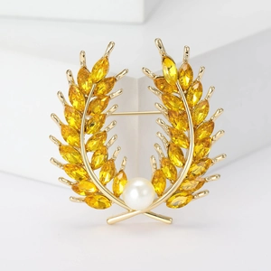 Élégante broche blé doré avec pierres marquises jaunes et perle sur socle blanc