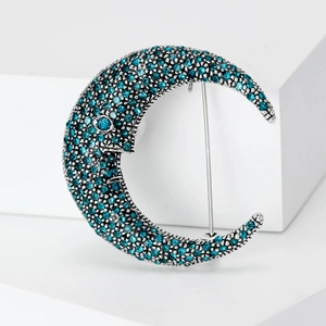 Vintage crescent moon face brooch with turquoise rhinestones and silver alloy base