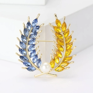 Vue détaillée d'une broche épi de blé avec cristaux bleus et jaunes et perle blanche