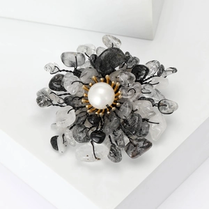 Macro shot of pearl flower brooch with natural stones and black wire craftsmanship