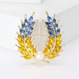 Élégante broche blé dorée avec cristaux bleus et jaunes et une perle blanche