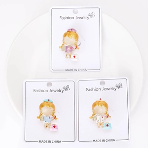 Gros plan de trois broches d'infirmière colorées en rose, bleu et blanc sur une carte de mode