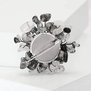 Elegant natural black rutilated quartz flower brooch on a white geometric minimalist stand