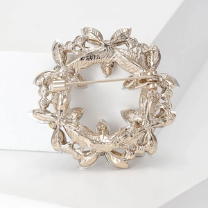 Elegant gold crystal wreath brooch with intricate leaf texture and secure back pin closure