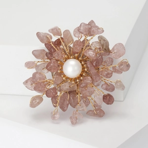 Detail shot of a handmade flower brooch with natural pink quartz and a large pearl center