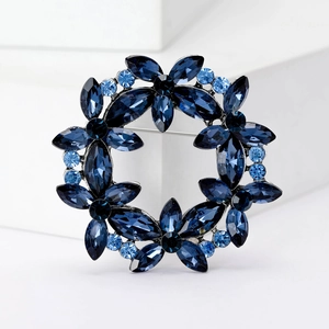 Detailed macro shot of a crystal wreath brooch featuring deep blue multifaceted gemstones