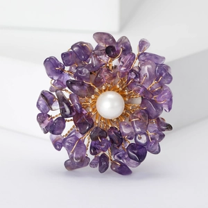Detailed macro view of amethyst stone flower brooch with white pearl and gold wire