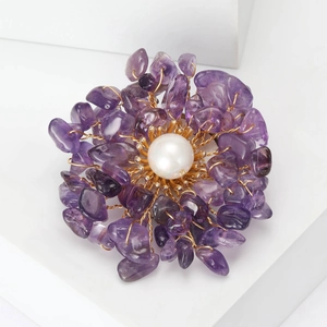 Macro shot of handmade flower brooch with purple crystals and central white pearl