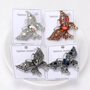 Detail of four butterfly brooches with colorful rhinestones set in a white ceramic bowl