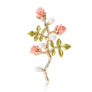 Élégante broche rose dorée avec pétales roses, feuilles vertes et perles sur fond blanc
