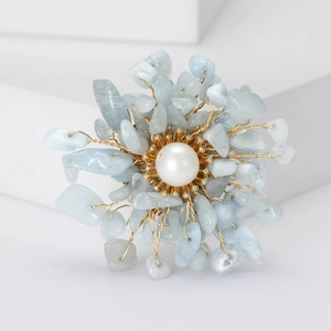 Macro shot of handmade flower brooch with natural blue stones and a white pearl center