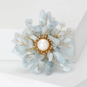 Macro shot of handmade wire-wrapped floral brooch with pearl and blue gemstones