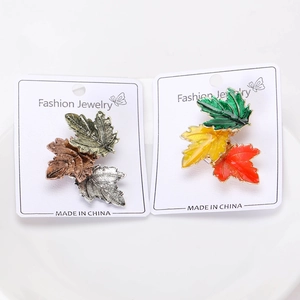 Detailed close-up of vintage metallic and colorful enamel maple leaf brooches