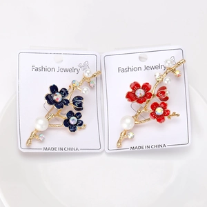 Détail des broches fleurs de prunier avec perles et incrustations en émail coloré