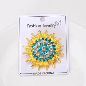 Macro detail of sunburst brooch with blue crystals and gold trim on display card