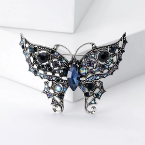 Close-up of vintage butterfly brooch with deep blue crystals and intricate hollow metalwork