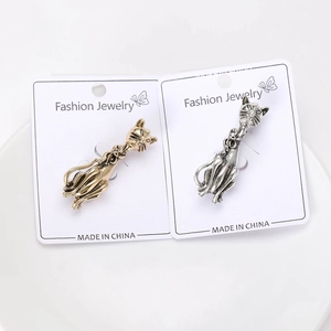 Detailed close-up of retro cat brooches in antique gold and silver on display card