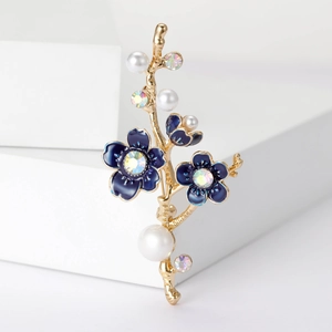 Détail d'une broche branche de prunier avec fleurs en émail bleu et perles blanches