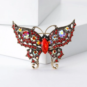 Vintage gold butterfly brooch with red crystals and rhinestones on white background