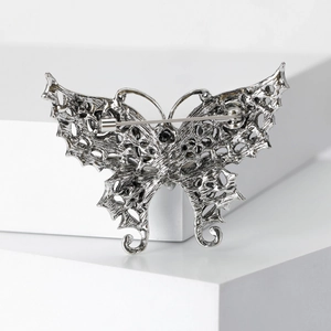 Vintage silver butterfly brooch with rhinestones shown on a geometric stone display