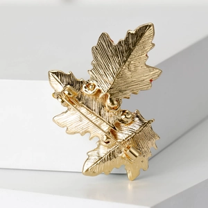 Back view of vintage golden maple leaf brooch with secure safety pin and brushed texture